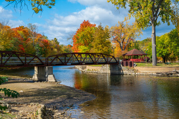 Fototapeta na wymiar Vibrant fall colors surrounding the bridge in Island Park Grand Ledge, MI