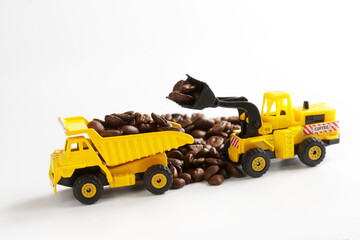 Toy forklift loads coffee beans into a dump truck. White background. The concept of transportation...
