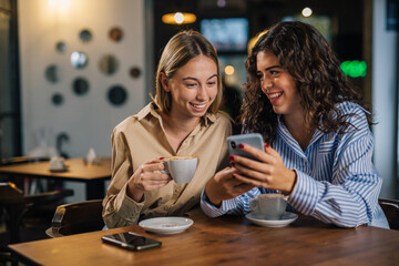 Two young women sit close in a cafe