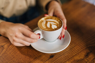 Close up view of hands holding a cup of coffee