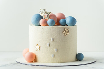 Baby shower party cake with white cream cheese frosting decorated with blue and pink chocolate spheres. Guess the gender of the upcoming child. He or She cake. Reveal the sex of the unborn baby.