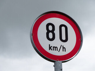 Round sign limiting speed, cloudy sky. Signs warning of a maximum speed of 80 km h