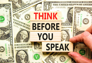 Think before you speak symbol. Concept words Think before you speak on wooden cubes. Beautiful background from dollar bills. Businessman hand. Business think before you speak concept. Copy space.