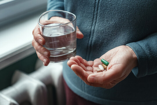 Woman holding a pill and a glass of water, ready to take her medicine. Sick woman needs to take pills for headaches, colds, painkillers, dietary supplement, feeling sick. The concept of health care