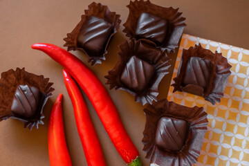 Chocolate sugar dessert with red chilli pepper on brown background
