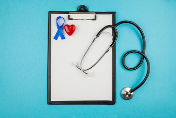  clipboard of stethoscope with sheet of paper blue silk ribbon and small red heart prostate cancer awareness symbol