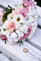 Wedding rings and bouquet on background