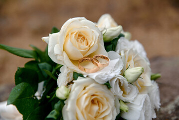 Wedding rings and bouquet on background