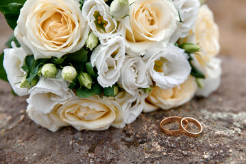 Wedding rings and bouquet on background