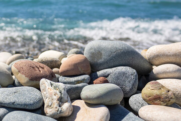 Fototapeta na wymiar Close-up of beach stones in front of blurred wavy sea