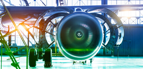 Repair maintenance of aircraft engine open hood on the wing of the plane. Industrial theme view in blue-green hue with bright sources of warm light. Format banner header wide size, place sample text. - obrazy, fototapety, plakaty