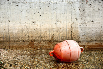 Boat fender. Old orange buoy and wall background