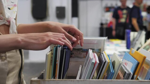 Hands choosing comics, child selecting book while visiting bookshop, kid boy searching and looking for a fairy tale book in bookstore or choose a book from a bookshelf in a