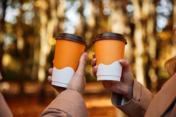 Friends drink cup of coffee together in autumn park