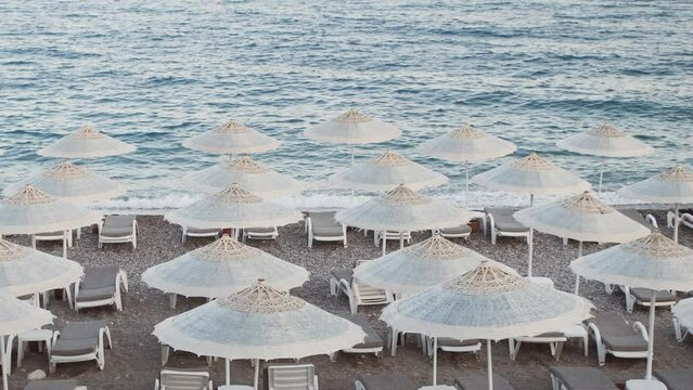 Empty Beach, Rows of folded beach umbrellas and empty sunbeds in Turkey, early morning. Italy or Greece. Top view. Travel and leisure concepts.