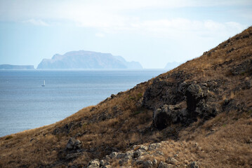 Lonely sailboat in the ocean. Islands in the haze on the horizon. Modeira. Seascape.