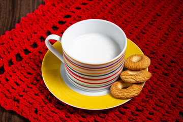 Ring Coconut biscuits and a cup of milk. Brazilian little donut. Selective focus and red platemate.