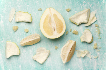 Close up ripe juicy fresh cut sliced yellow Pomelo on mint blue color cement background. Shaddock, citrus maxima, tropical fruit. Top view. Flat lay. 