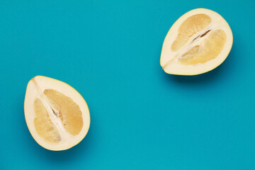 Close up ripe juicy fresh cut sliced yellow Pomelo on blue color background. Shaddock, citrus...