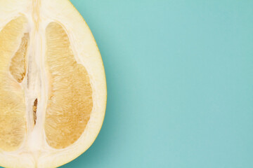 Close up ripe juicy fresh cut sliced yellow Pomelo on mint blue color background. Shaddock, citrus...