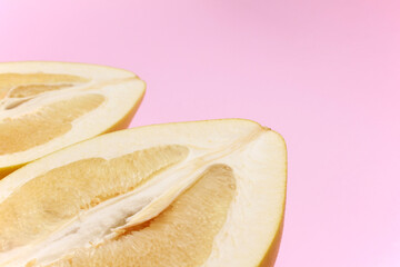 Close up ripe juicy fresh cut sliced yellow Pomelo on pink color background. Shaddock, citrus...