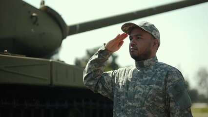 Soldier man in military uniform special forces saluting standing against on field Mission. Commander Army soldier military defender of  nation in uniform standing near battle tank while state of war.