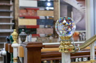 Faceted glass ball with multi-colored highlights is mounted on a wooden staircase.