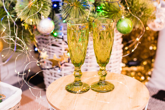 Glasses of sparkling champagne near the Christmas tree, garland and Christmas decoration. Christmas and New Year celebrations.