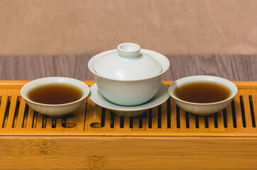 Cups, chaban selective focus. Gongfu cha tea ceremony. Zhu-yao Chinese ceramics on a bamboo tea board. Brewing Chinese tea in ceramic dishes gaiwan, chahai, cups during the tea ceremony close-up.