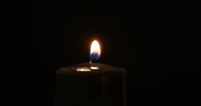 lights black paraffin candle using a match on a dark background. Bright flame, fire, ignition. Concept of memory, ritual, celebration, problems with electricity, energy crisis, war in Ukraine.