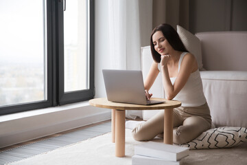 work from vacation home, remote workers. Working from Anywhere.  woman freelancer connecting to the Internet from home. The adorable  young woman using a laptop, in a stylish living room. 