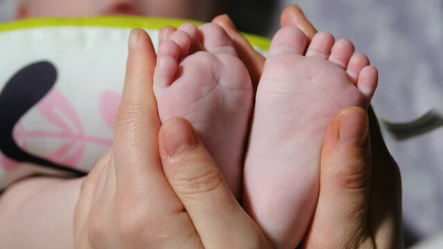 Caring mom holds baby feet in her hands. Baby feet in mothers hands. The Bottom of a Babys Foot. Happy Mother and her baby are playing together. Happy family concept. Childcare happy childhood. 4k