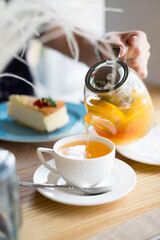man poured orange tea from a teapot into a mug, morning breakfast table, man hand, breakfast for two