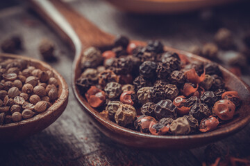 Pepper spice mix in spoon and variety spices at table background. Dried spice and seeds