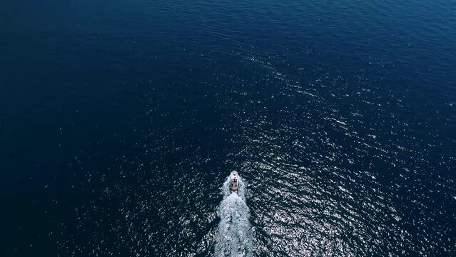 Aerial view of a boat on the Amalfi Coast, Italy. Drone slow motion footage with smooth camera movement. Sea waves diverge from the movement of the yacht on a sunny day