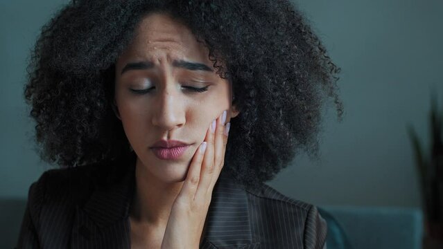 African girl businesswoman student woman with curly hairstyle suffer from toothache sick female touch cheek feel teeth pain has sensitive ailing bleeding gums caries dental health problem with hygiene