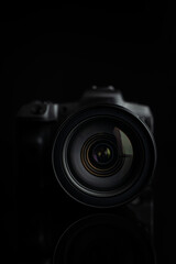 Digital mirrorless camera on black background. Lens closeup. Front view.