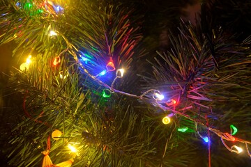 Obraz na płótnie Canvas Closeup of Christmas tree decorations. Lights on Christmas tree. Christmas and New Year decorations on Christmas tree. Christmas tree with decorations - straw ornament