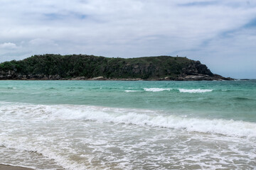 Linda praia das Conchas, próxima a cidade de Cabo Frio, com mar azul em volta, céu com nuvens e...