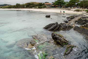 Linda praia do forte em volta do Forte São Mateus em Cabo Frio, com muitas Rochas, a água do mar correndo entre elas e suas areias brancas.