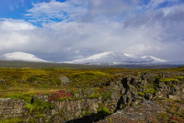 Thingvellir National Park, Iceland: Volcanic rock in the foreground; snow-covered mountains in the distance.