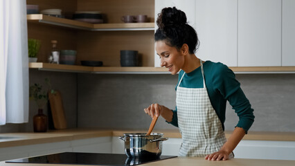 Female chef arabian woman cooker wife mother cooking aromatic dish on stove at home kitchen...