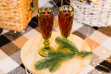 Concept of Christmas celebration and home comfort. Glasses with red wine on a table under a Christmas tree decorated with a garland and balls