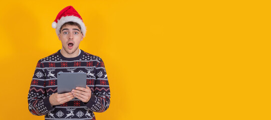 young santa claus isolated looking at tablet or laptop surprised