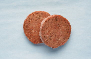two servings of frozen red meat patties, preparation for burgers