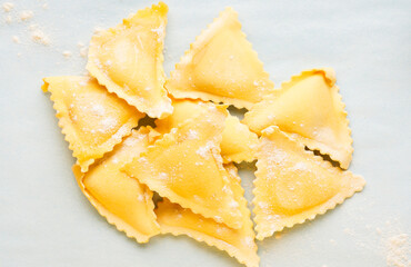 A group of delicious triangular frozen ravioli on a blue background. Appetizing frozen food