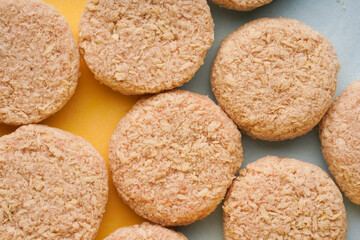 many large patties for frying in breading on a colored background