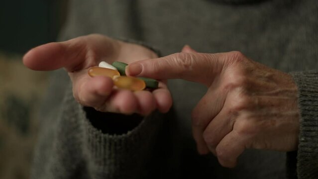 Elderly Female Hands Holding Medicine Pills On Hand. Unrecognised Senior female counting medicine drugs in hands.