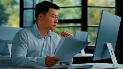 Desperate sad asian japanese senior specialist businessman sit at office read documents scam...