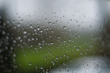 Rain drops cast on a window in early morning. A soft focus garden through the glass. Typical English weather and wintery scene. copy space.